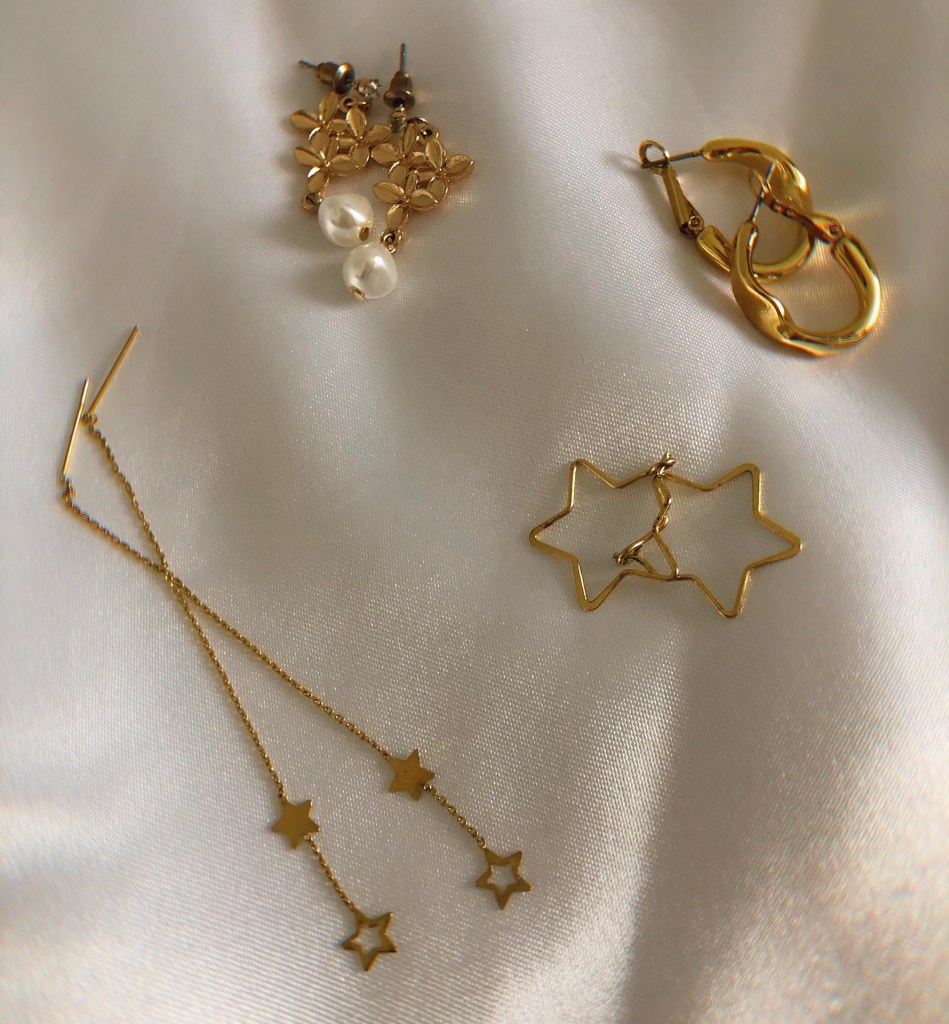 Gold jewellery laid out on a white silk cloth.