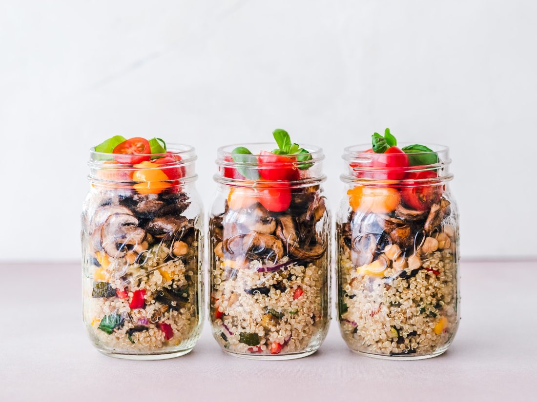 Meal prep jars filled with quinoa and vegetables.